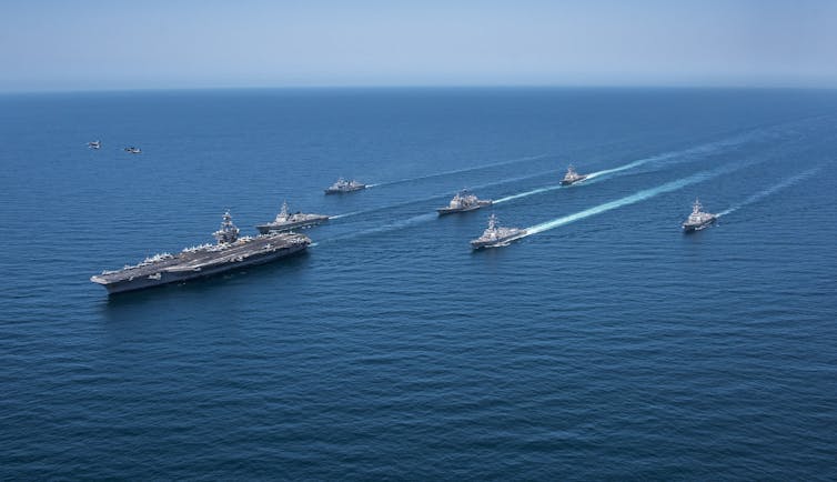 A large ship is trailed by smaller boats.