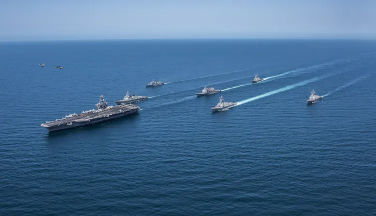 A large ship is trailed by smaller boats.