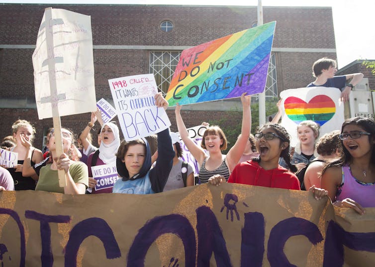 La gente protesta, una con un signo