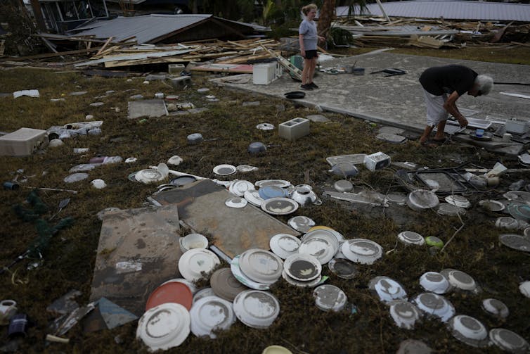 A woman and a child sift through the detritus where a business once stood.