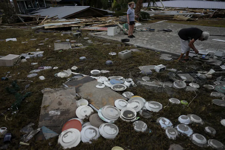 A woman and a child sift through the detritus where a business once stood.
