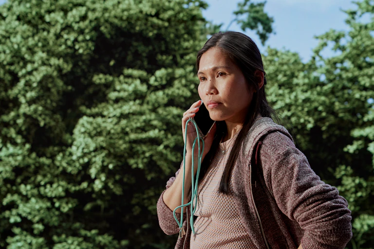 a woman stands with a phone to her ear.