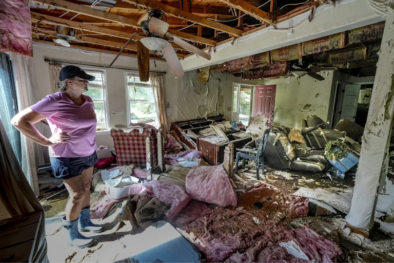 A woman surveys her damaged house.