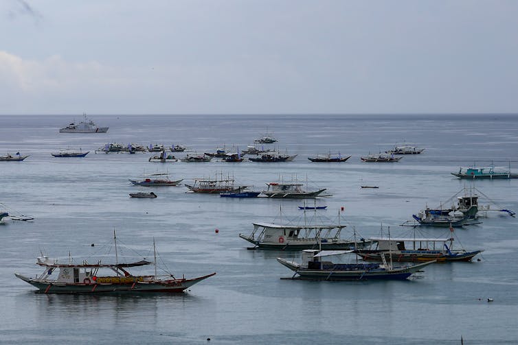A dozen or so small ships are seen at sea.