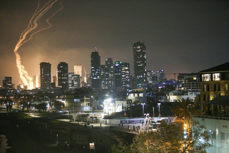 A city skyline is lit up by a missile strike