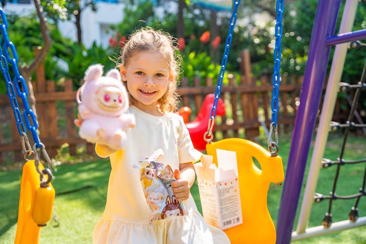 A girl holds up a labubu.