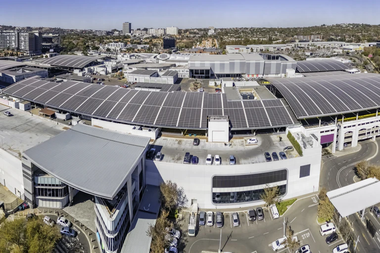 A mall photographed from the sky showing dozens of solar panels mounted on its roof