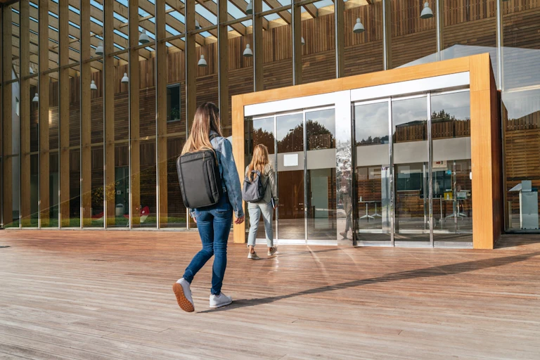 Deux étudiantes se dirigent vers la porte d'entrée d'une université.