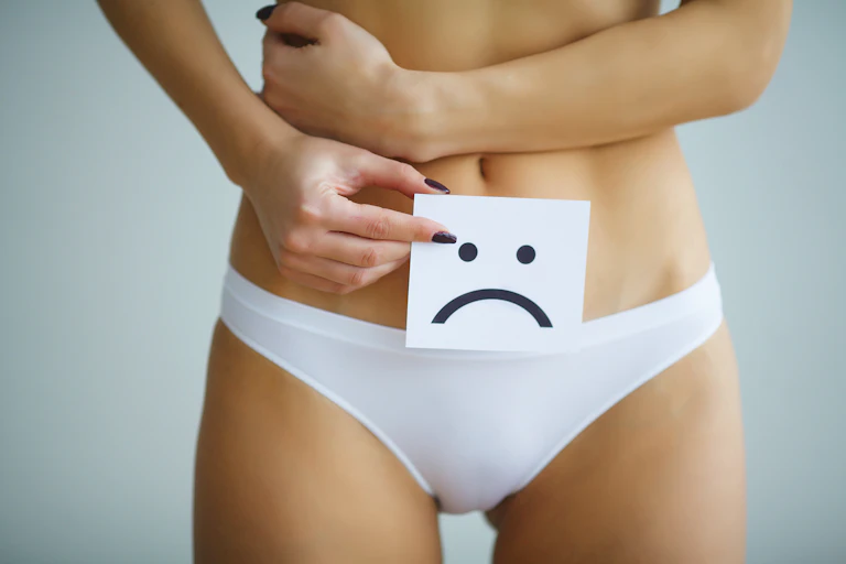 Woman holding sad smiley card over genital area