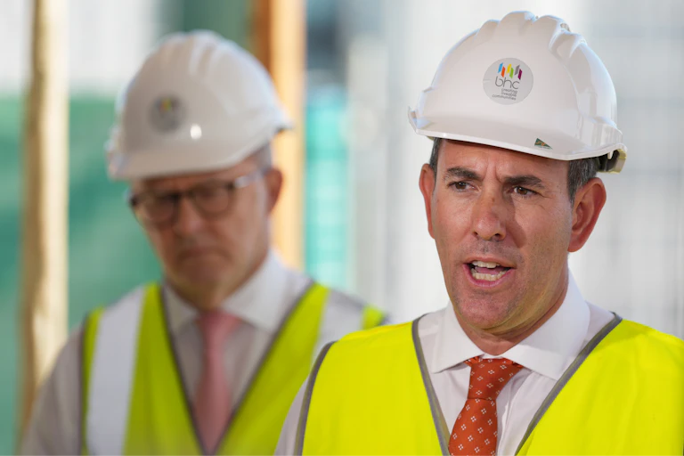 A man dressed in a hard hat and high vis vest over a shirt and tie.