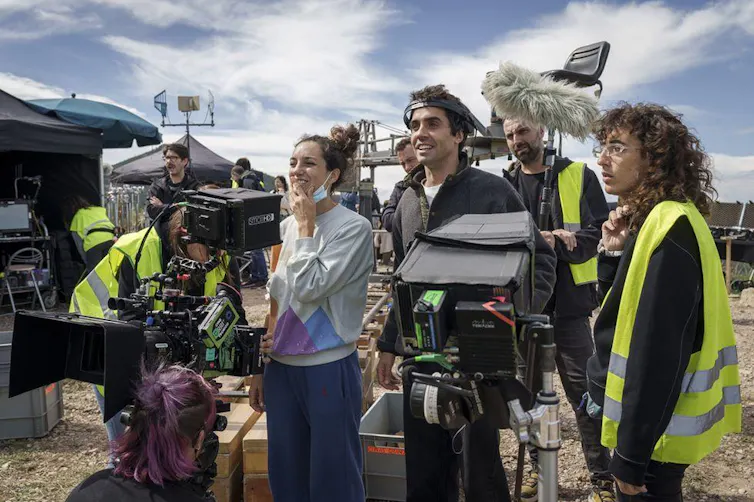 Gente observa algo fuera de campo situados detrás de cámaras de cine.