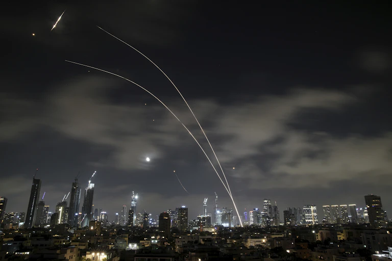 Plumes of light in a night-time sky over a city