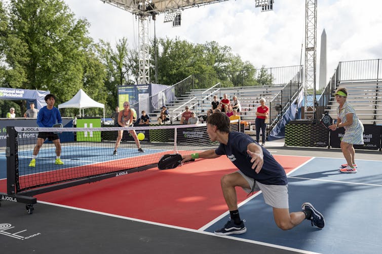 The teenager returns the hit over the net on the picklebol pitch in a double match