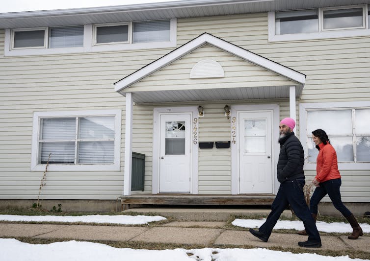 4 razones para la preocupación por C-4 amenazan en la privacidad y la soberanía canadiense 1 Dos personas, un hombre con un gran turbante rosado, caminando por la calle residencial nevada.