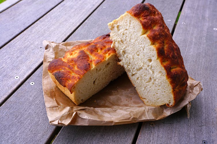A cut loaf of fresh rēwena, a potato sourdough Māori bread, on a brown paper bag.