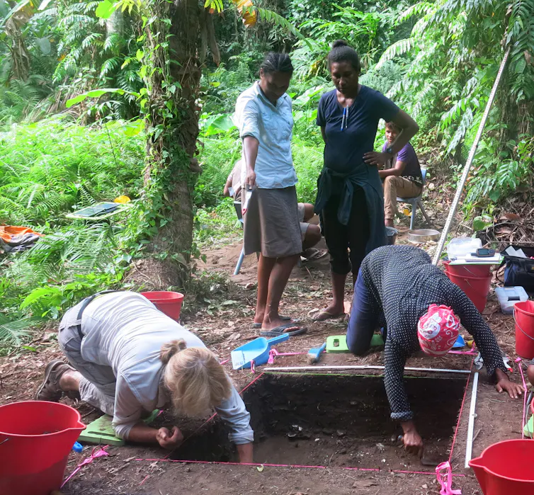 Four people excavating an archaeological site with trowels
