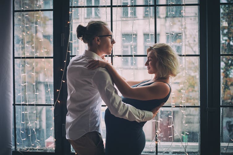 A man and a pregnant woman dancing together.
