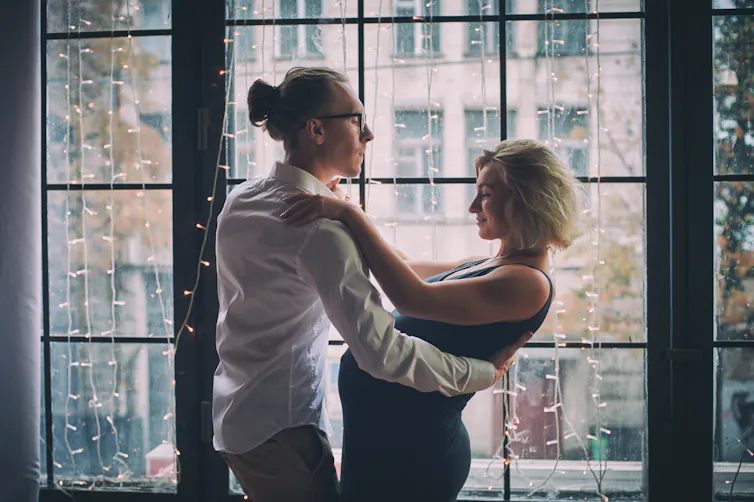 A man and a pregnant woman dancing together.