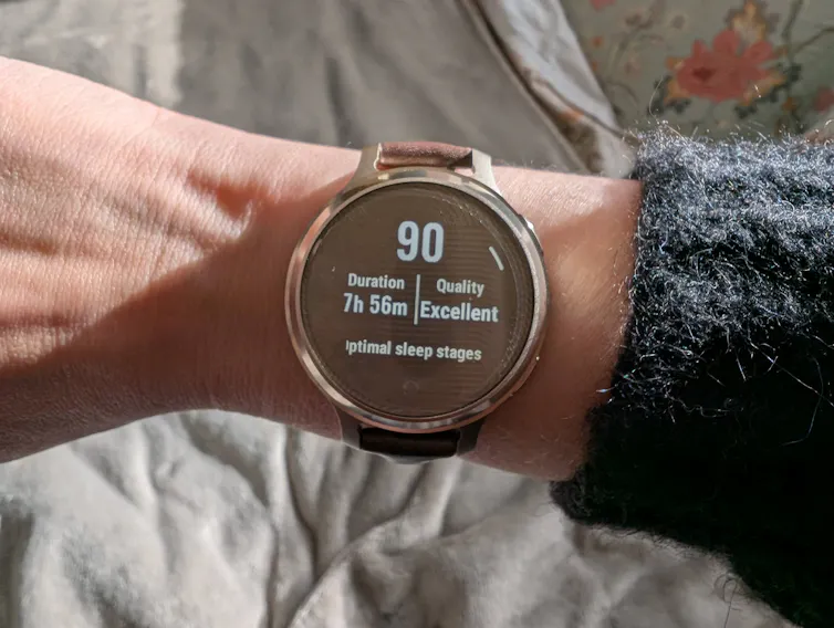 A woman's wrist with a large smartwatch displaying a sleep score, length and 'optimal sleep phases'.