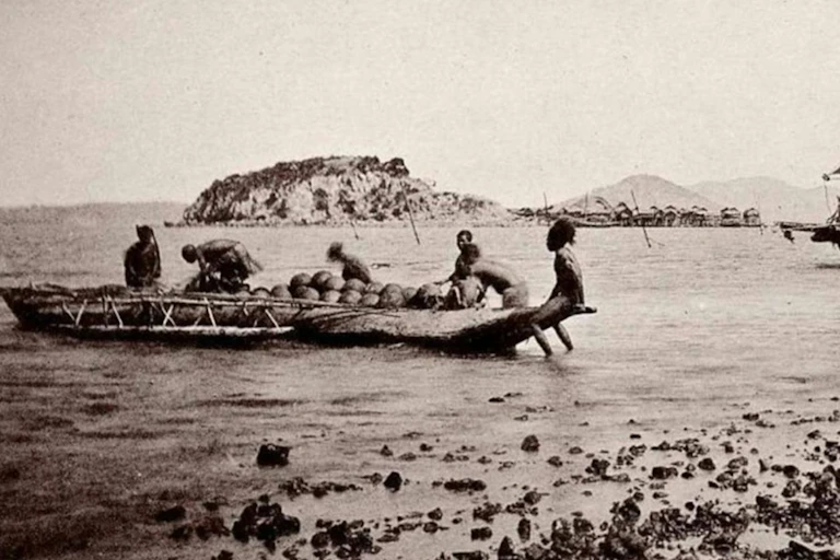 Historical photograph: women load an outrigger canoe with earthenware pottery.