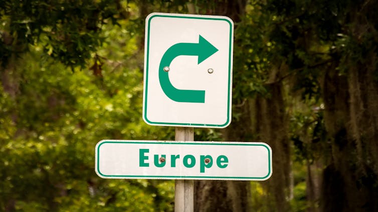 A street sign showing an arrow going back on itself, pointing to Europe/