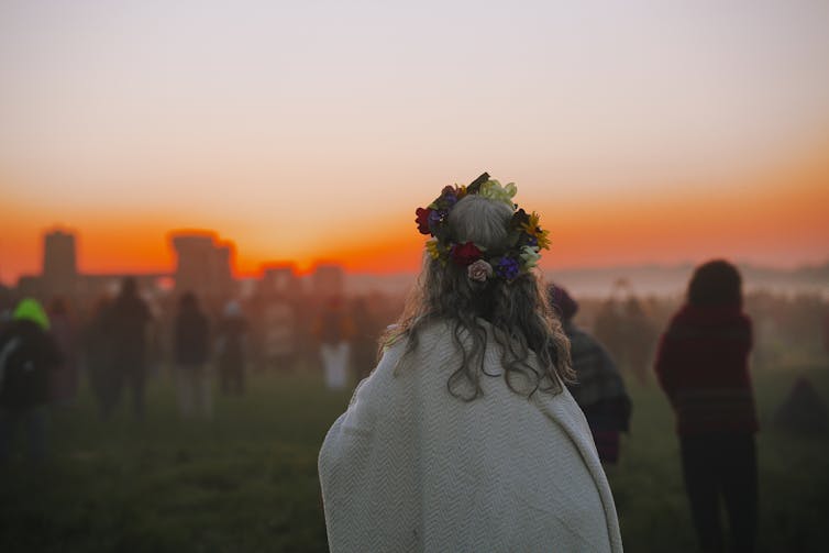 Woman wearing flower crown at Stonehenge at sunset