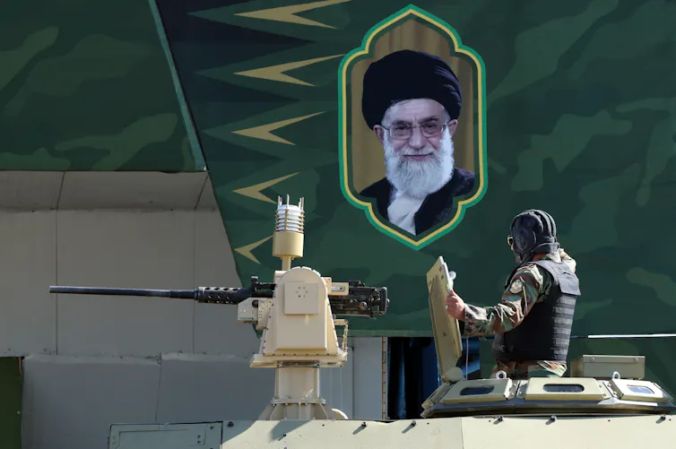 A tank rolls next to a picture of Khamenei.
