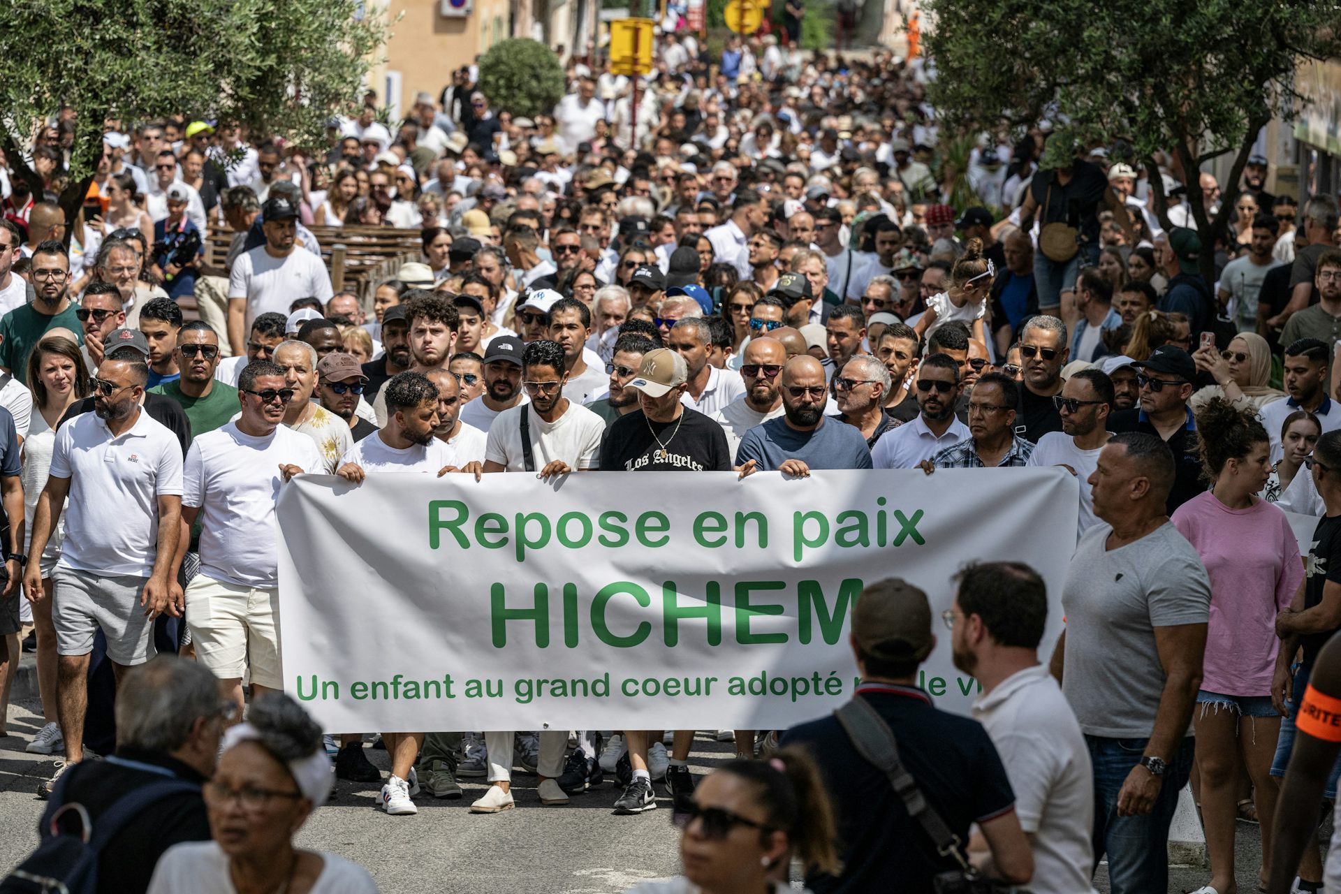Les participants brandissent une pancarte sur laquelle on peut lire « Repose en paix, Hichem. Un enfant au grand cœur, adopté par le village » lors d'une Marche Blanche à Puget-sur-Argens, dans le sud de la France, le 8 juin 2025