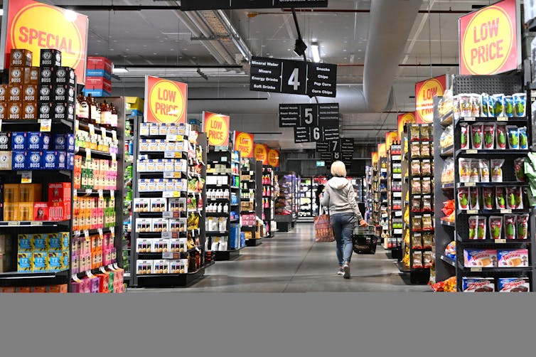 A woman walking down a supermarket aisle.