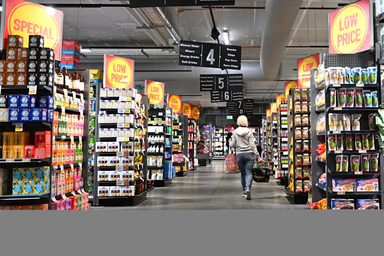 A woman walking down a supermarket aisle.