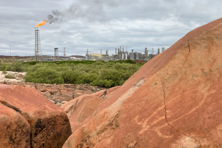 The North West Shelf gas project in the background with a petroglyph of a turtle at Murujuga Cultural Landscape in Burrup Peninsula, Western Australia