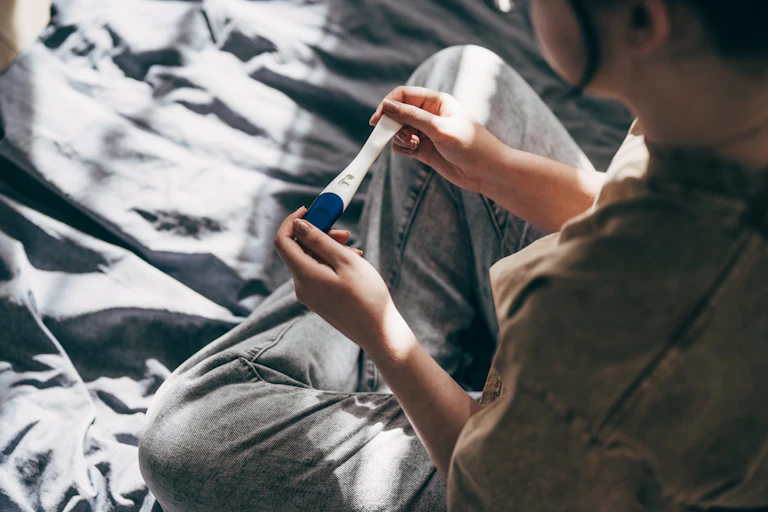 Rear view of a woman taking a pregnancy test at home
