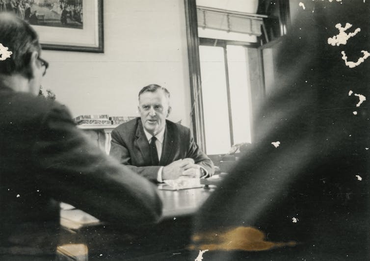 Archival photo: Joh at a conference table.