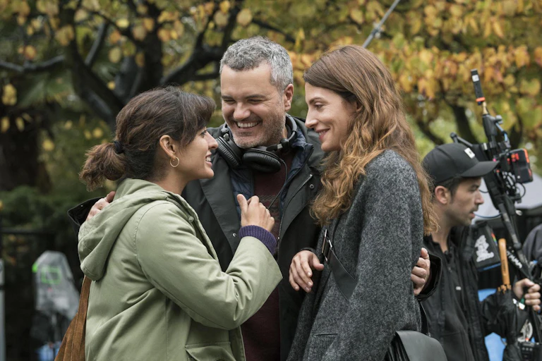 Dos mujeres y un hombre charlan sonrientes.