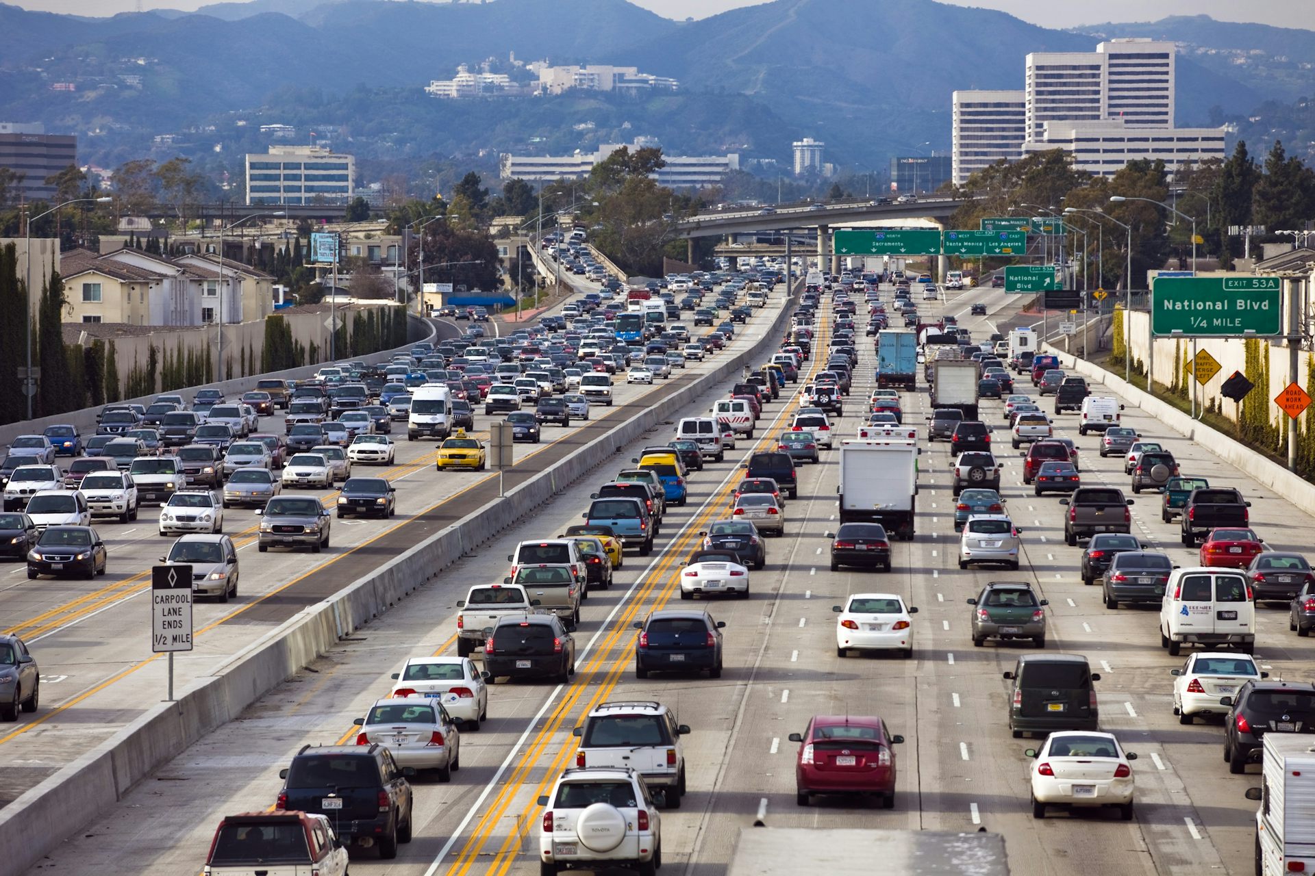 Una autopista de seis carriles en cada sentido llena de coches.