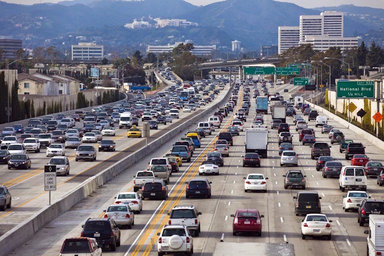 Una autopista de seis carriles en cada sentido llena de coches.