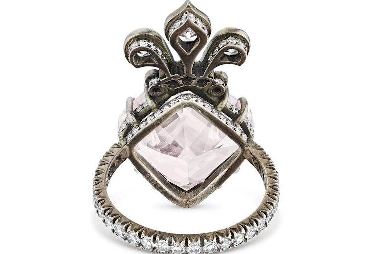 Light pink diamond set in a ring with a fleur de lis design above the stone