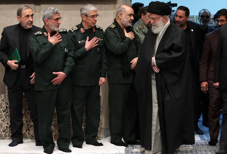 A man in traditional Iranian dress meat a group of men in army fatigues.