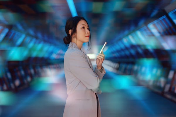 A businesswoman holding a smartphone stands in front of a computer generated background