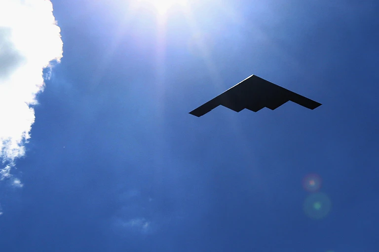 Photo of a B2 bomber against a blue sky and sun
