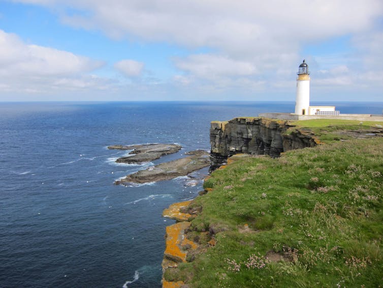 A lighthouse on the edge of dramatic cliffs.
