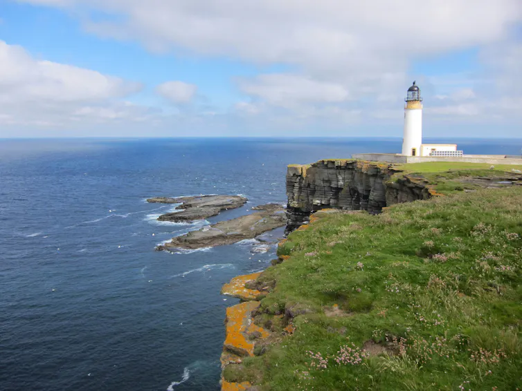 A lighthouse on the edge of dramatic cliffs.
