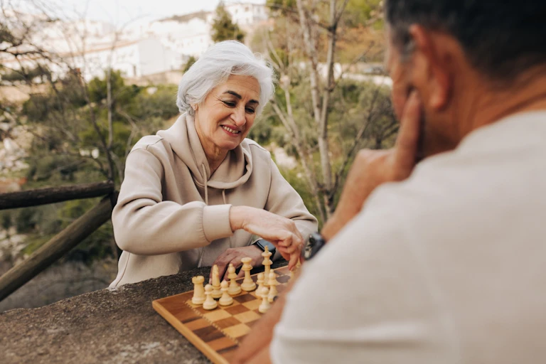 femme âgée joue aux échecs à l'extérieur avec un homme