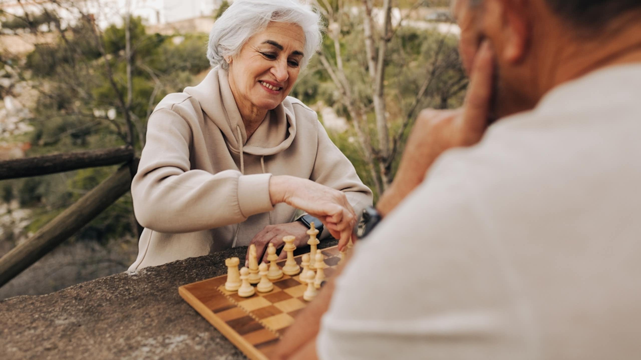 femme âgée joue aux échecs à l'extérieur avec un homme