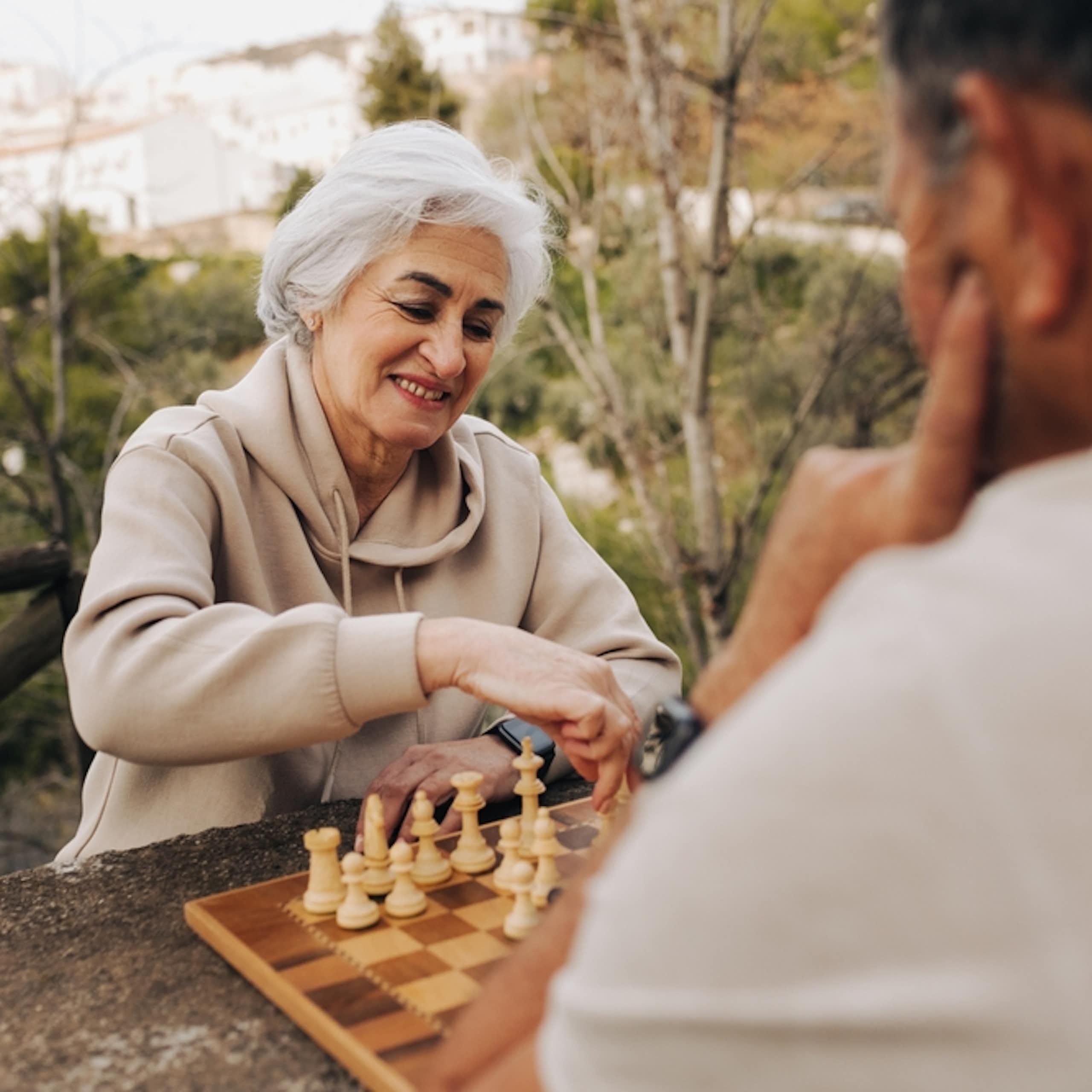 femme âgée joue aux échecs à l'extérieur avec un homme