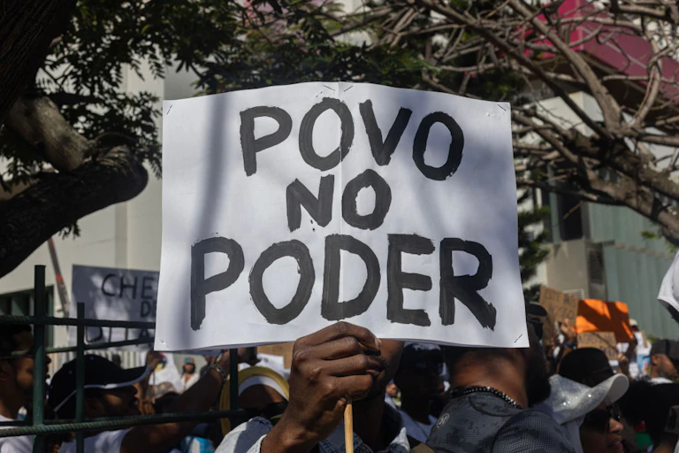 A man holds a banner that says "povo no poder"