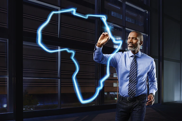 A man appears to draw the outline of the continent of Africa, using a light pen