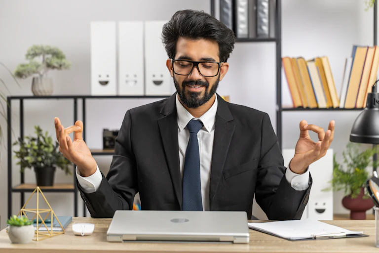 Man in a suit in office environment takes moment to meditate during working day