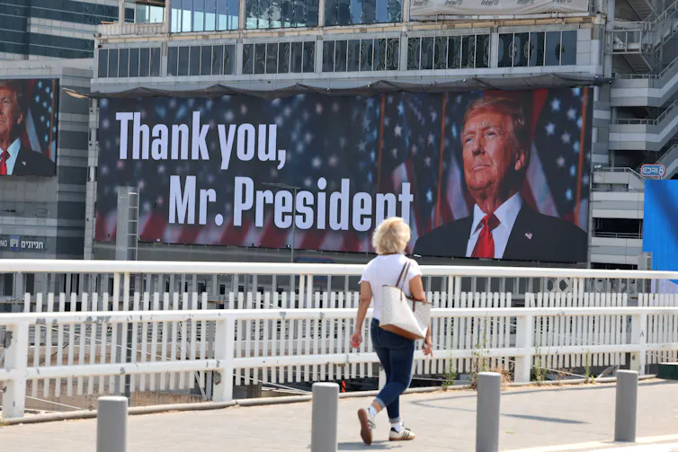 A woman walks past a billboard in Tel Aviv saying: 'Thank you Mr President'.