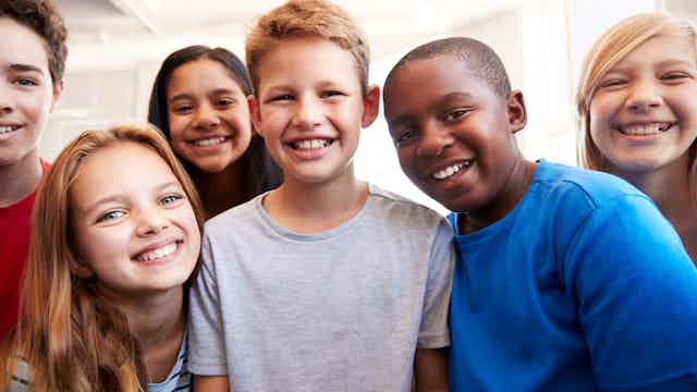 A group of elementary school children crowding before the camera and smiling.